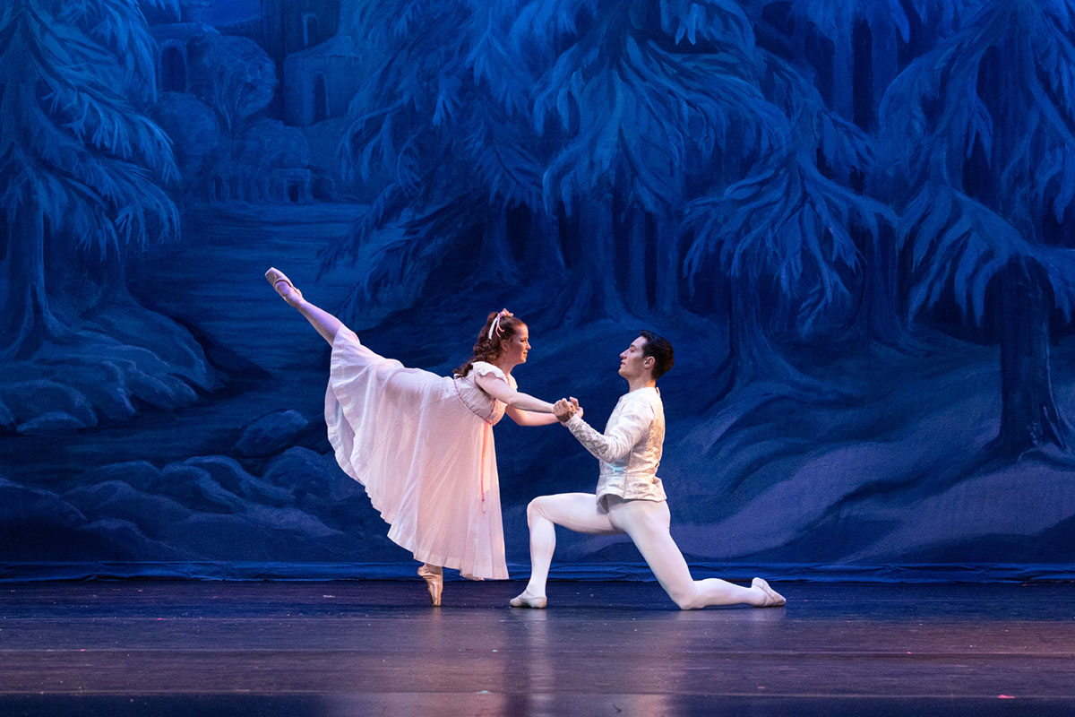 Nutcracker dancers with prince kneeling and supporting Clara in attitude.